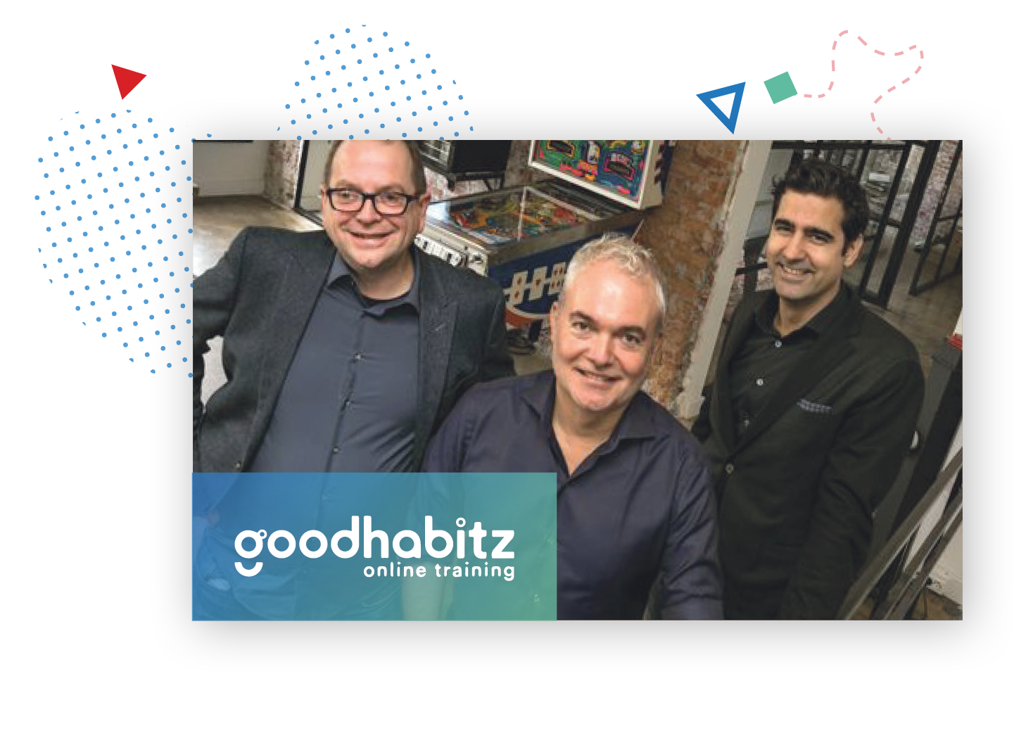 picture of three GoodHabitz employees smiling at the camera from their office, with in the background a pinball machine